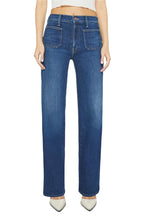 A person wearing the Mother Denim Petites Lil Patch Pocket Rambler Zip Sneak jeans, characterized by their high-waisted and wide-leg stretch denim design with front pockets, pairs them with white pointed shoes while standing against a white background.