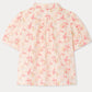 Back view of the Girls’ Mathilda Blouse by Bonpoint, crafted from soft organic cotton in light pink and adorned with a Paris-themed floral print featuring flowers, the year 1975, and the word “Repetto” in a repeating pattern.