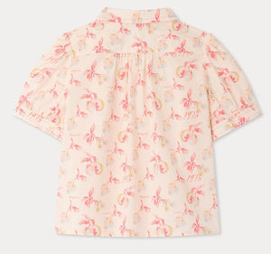 Back view of the Girls’ Mathilda Blouse by Bonpoint, crafted from soft organic cotton in light pink and adorned with a Paris-themed floral print featuring flowers, the year 1975, and the word “Repetto” in a repeating pattern.