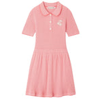 The Girls’ Marlie Dress by Bonpoint is a pink short-sleeve knit dress for girls, featuring a collar, three front buttons, a subtle gingham print, and a small cherry embroidery on the chest.