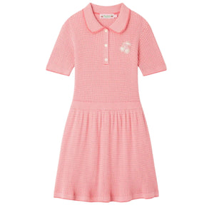 The Girls’ Marlie Dress by Bonpoint is a pink short-sleeve knit dress for girls, featuring a collar, three front buttons, a subtle gingham print, and a small cherry embroidery on the chest.