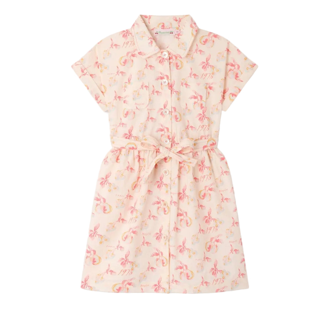 The Girls’ Gisele Dress by Bonpoint is a short-sleeved, collared, button-down shirt dress crafted from organic cotton with a pink and yellow floral print and a matching waist tie, shown against a white background.