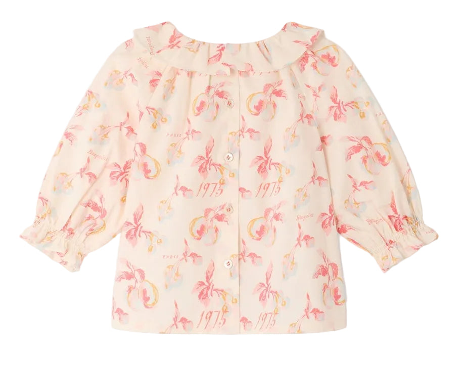 Introducing the Baby Girls’ Dolci Blouse by Bonpoint—a light pink children’s blouse featuring a ruffled collar, button-front closure, and a playful print of pink palm trees with yellow accents and the number “1975” scattered throughout. Crafted from soft organic cotton for all-day comfort, this charming floral print baby blouse is perfect for any occasion.