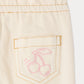 Close-up of a cream-colored, cotton-rich pocket with orange stitching and a pink outline drawing of two cherries, featured on the Bonpoint Baby Girls’ Luciole Pant—perfect for adding a charming embroidered accent to organic babywear.