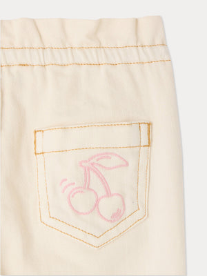 Close-up of a cream-colored, cotton-rich pocket with orange stitching and a pink outline drawing of two cherries, featured on the Bonpoint Baby Girls’ Luciole Pant—perfect for adding a charming embroidered accent to organic babywear.