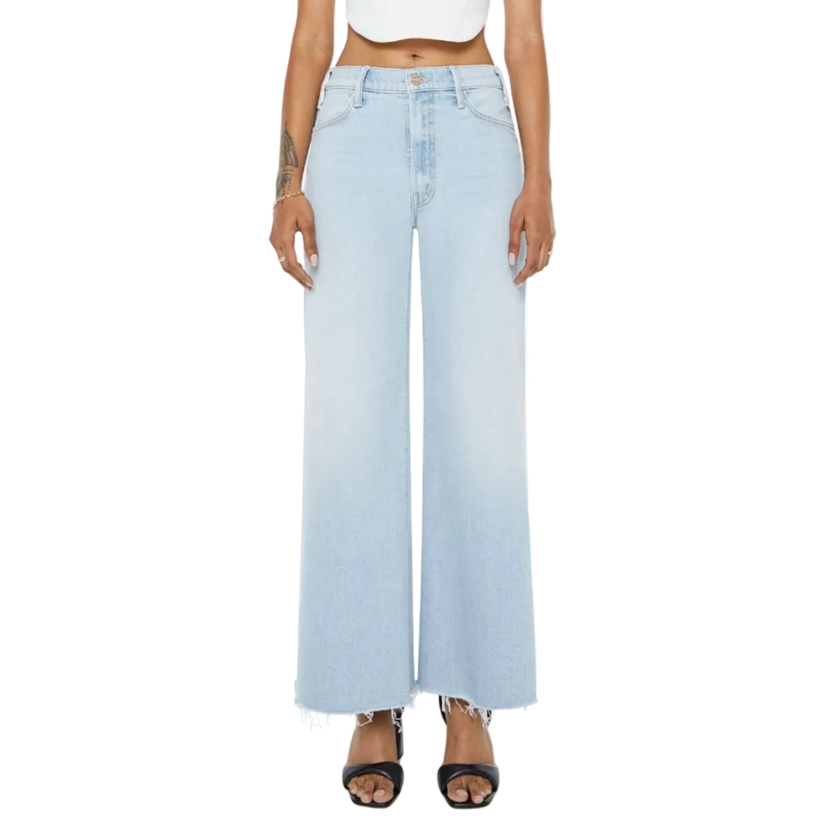 Model wears the Mother Petites Lil Hustler Roller Fray high-waisted, light-wash wide leg jeans with raw hems—ideal for petite denim options—styled with black heeled sandals and a white crop top; shown from the waist down against a white background.