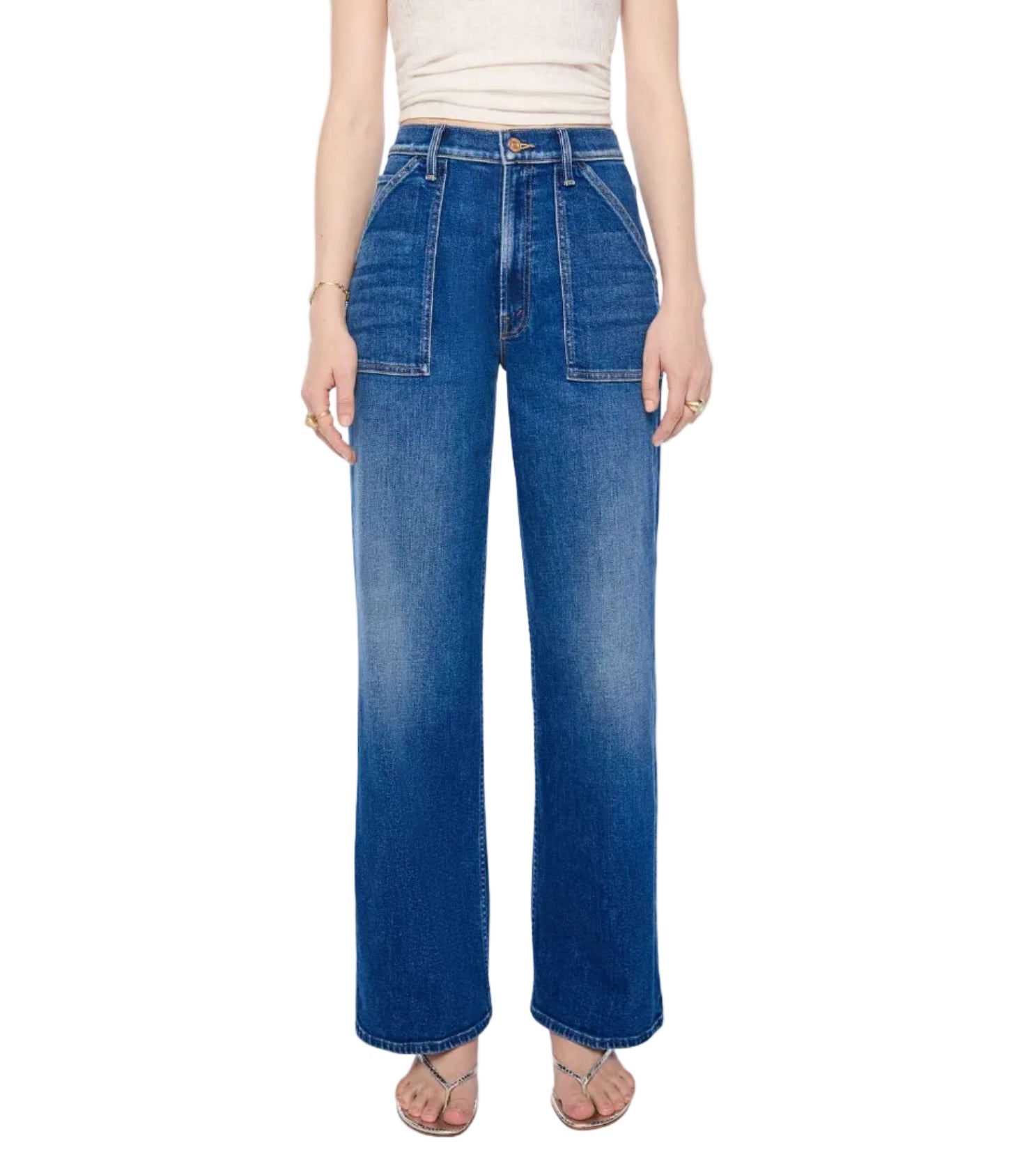A person is wearing the Mother Petites Lil Patch Maven Sneak—high-waisted, wide-leg blue jeans made from recycled stretch denim with front patch pockets—paired with a white sleeveless top and sandals, standing against a white background.