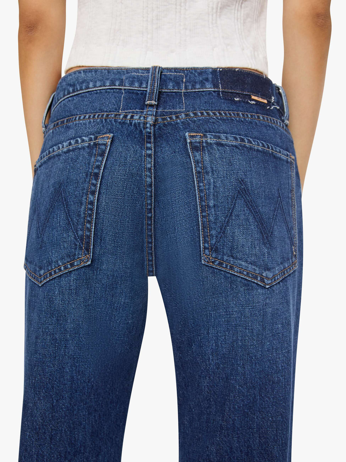 Back view of Mother Petites Lil Bookie Twist Skimp mid-wash mid-rise bootcut denim jeans with back pockets featuring an embroidered M logo.