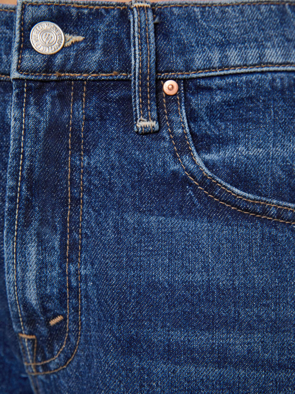 Close-up of the waistband and front pocket of dark blue Petites Lil Bookie Twist Skimp jeans, featuring copper-colored rivets and stitching.