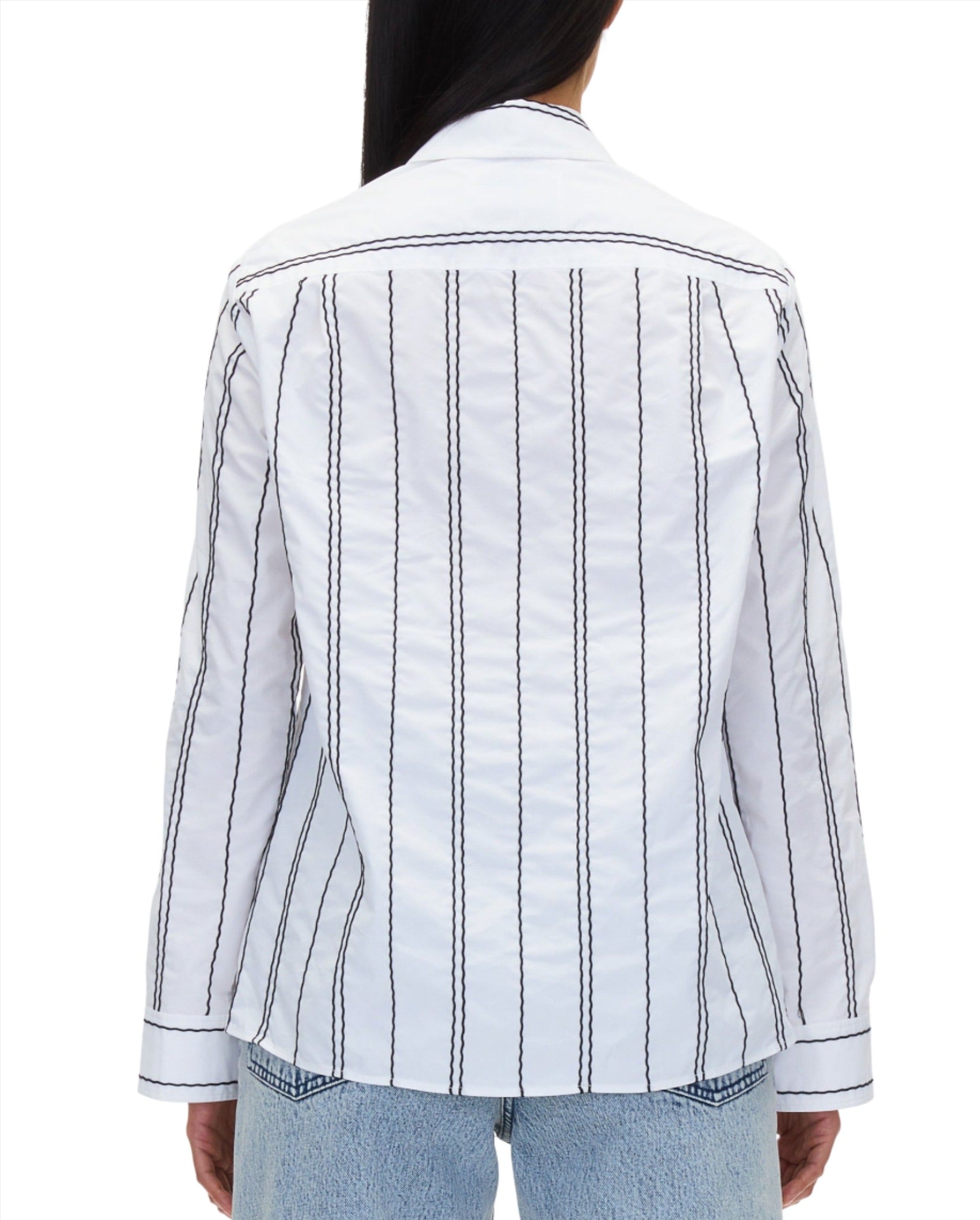 A person is seen from the back wearing a 3.1 Phillip Lim Poplin Shirt with Wave Embroidery, featuring black vertical stripes on a white background and an embroidered wavy stripe. The shirt has long sleeves and offers a relaxed fit, making it an ideal match with light blue jeans.