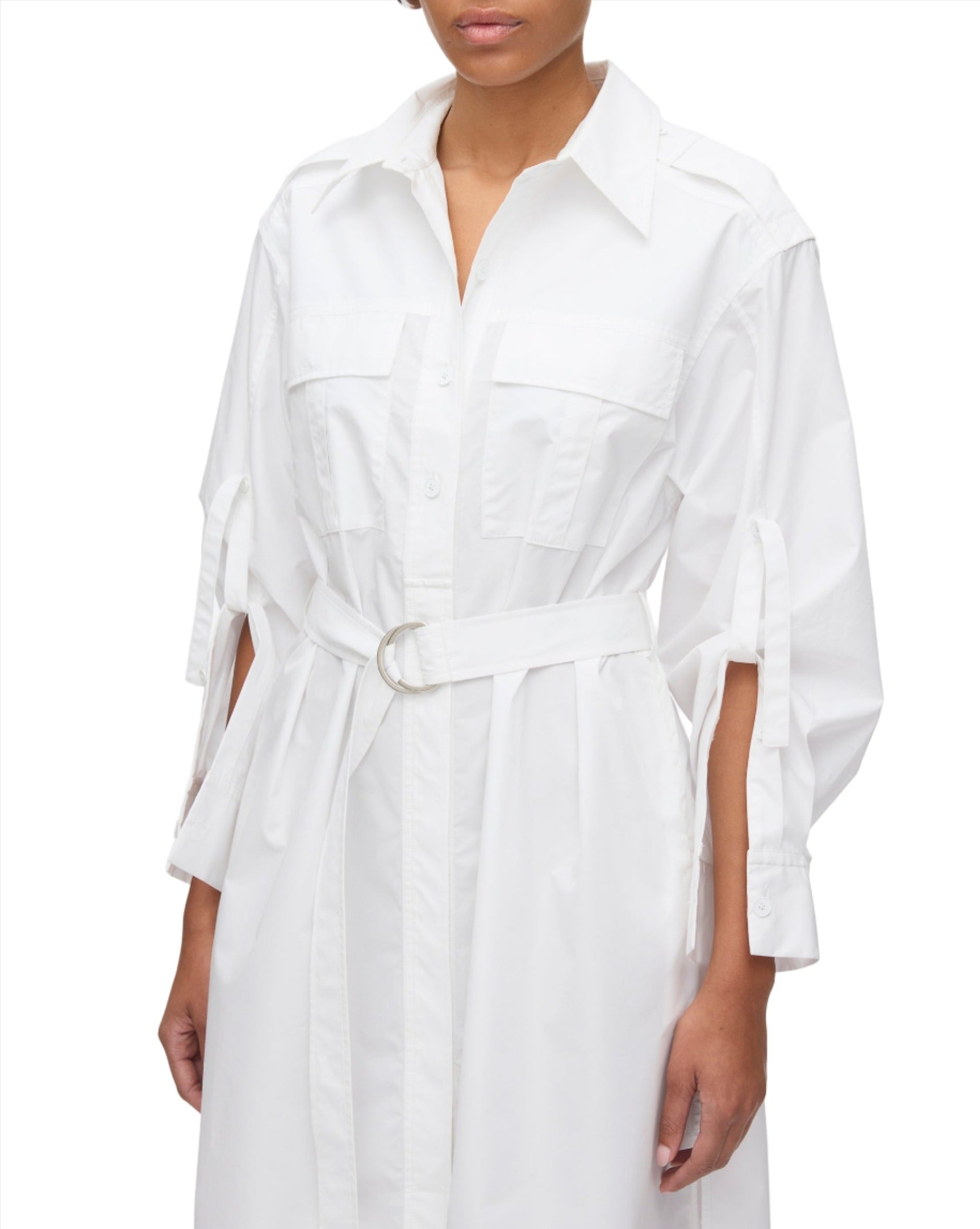 The individual is wearing the 3.1 Phillip Lim Poplin Utility Midi Shirt Dress, a chic white midi-length shirt dress featuring rolled-up sleeves and a belt, made from technical poplin for a crisp appearance.