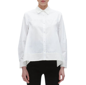 A person wears the Flounce Hem Poplin Shirt by 3.1 Phillip Lim—a long-sleeved, white collared button-up with an asymmetric hem—paired with black pants, shown from the front against a white background.