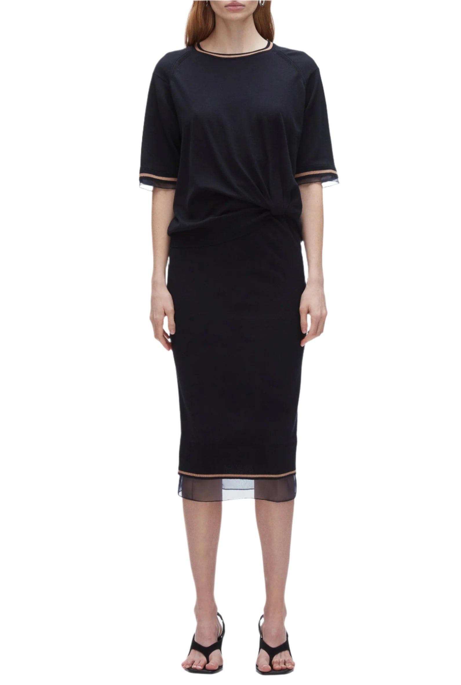 A woman wears the 3.1 Phillip Lim French Tuck Knit Dress with Organza, a black merino blend dress with mesh-trim hem, styled with a French tuck and paired with black heeled sandals.