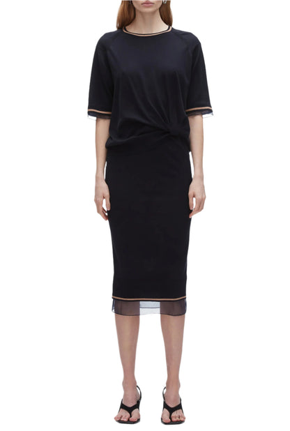 A woman wears the 3.1 Phillip Lim French Tuck Knit Dress with Organza, a black merino blend dress with mesh-trim hem, styled with a French tuck and paired with black heeled sandals.