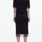 A woman stands with her back to the camera, wearing the 3.1 Phillip Lim French Tuck Knit Dress with Organza, styled with black heeled sandals.