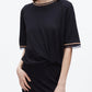 A woman wears the 3.1 Phillip Lim French Tuck Knit Dress with Organza, featuring black short sleeves and tan-and-black trim on the collar and sleeves.