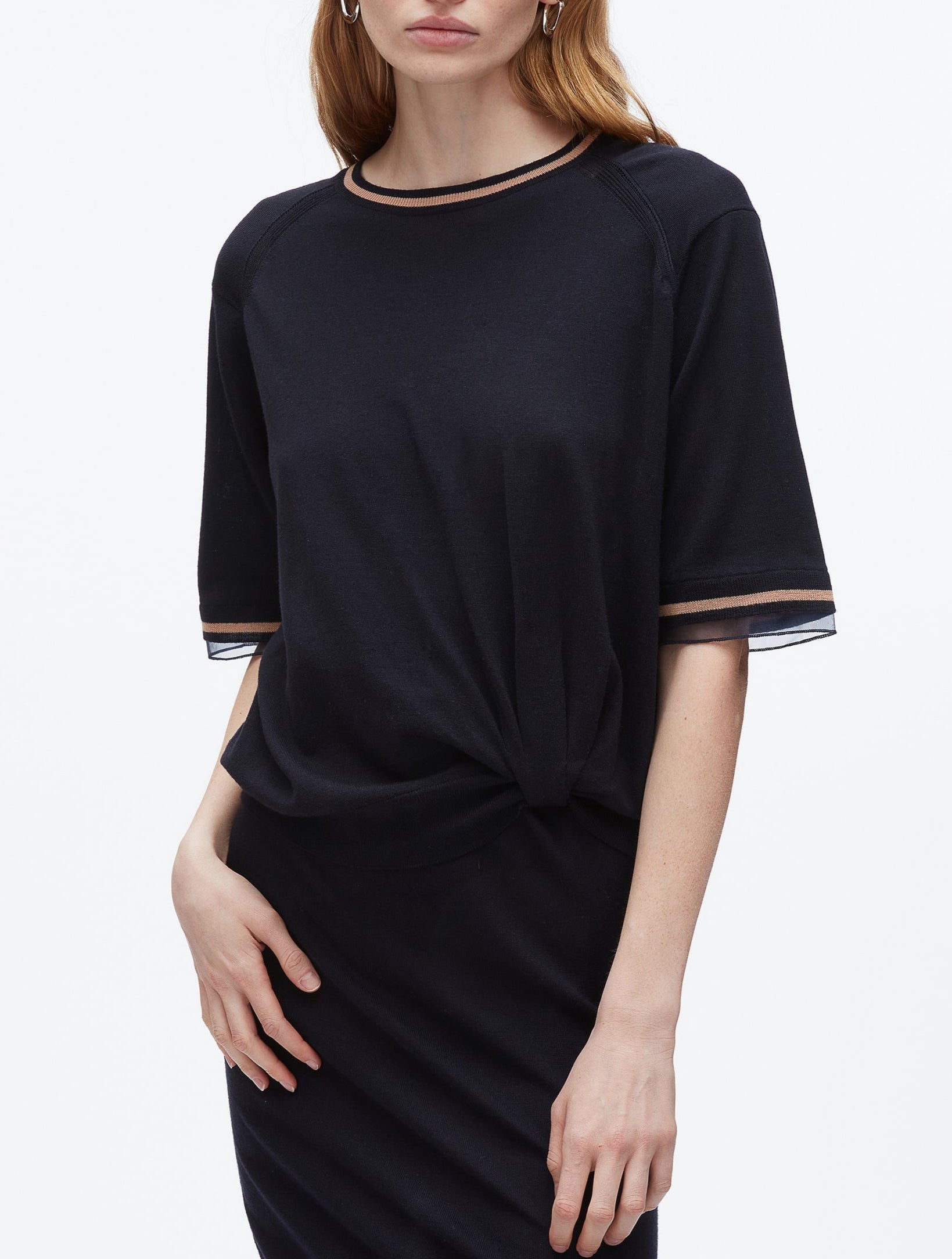 A woman wears the 3.1 Phillip Lim French Tuck Knit Dress with Organza, featuring black short sleeves and tan-and-black trim on the collar and sleeves.