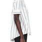 A person in profile wears the Adam Lippes Trapeze Stripe Shirt, featuring loose-fitting short sleeves and ivory and black stripes.