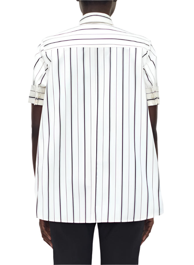 Photographed from behind, a person wears the Adam Lippes Trapeze Stripe Shirt—a short-sleeved, button-up design with ivory and black stripes in Italian cotton.