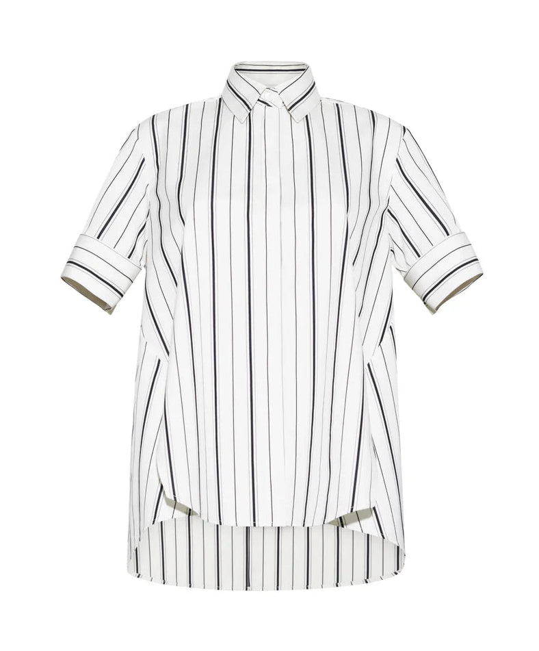 The Adam Lippes Trapeze Stripe Shirt is crafted from Italian cotton with ivory and black stripes, short sleeves, a pointed collar, and a slightly longer back hem.