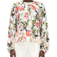 A person wears the Adam Lippes Lottie Top, a long-sleeve crepe de chine blouse with an ivory floral motif, paired with white pants and shown from the front.