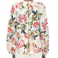 A person is seen from the back wearing the Adam Lippes Lottie Top, a long-sleeve white crepe de chine blouse with an ivory floral motif, paired with white pants.