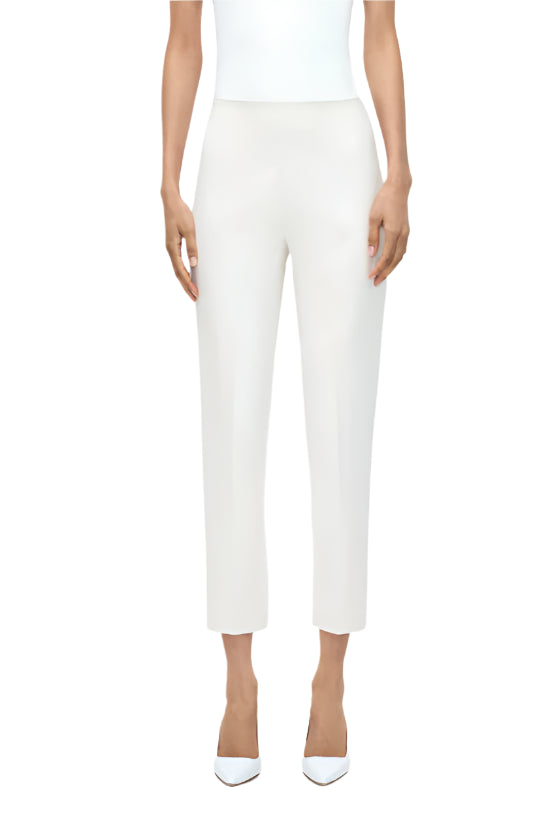 A person wears the Adam Lippes Kit Pant with a sleeveless white top and pointed-toe shoes, standing against a plain white background to showcase a sleek, modern silhouette.