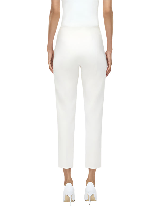 A woman is seen from the back wearing the Adam Lippes Kit Pant with a white sleeveless top and high-heeled shoes, creating a sleek, modern silhouette against a plain background.