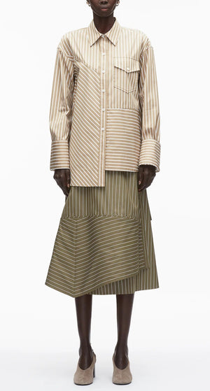 Wearing the 3.1 Phillip Lim Asymmetrical Stripe Trapeze Shirt, a person pairs it with an olive green striped midi skirt and taupe heels, standing against a plain background.