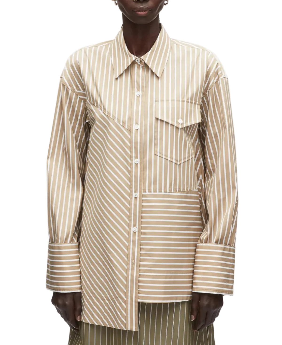 A person wears the 3.1 Phillip Lim Asymmetrical Stripe Trapeze Shirt, featuring beige and white mixed stripes, an asymmetrical chest pocket, and a relaxed silhouette.
