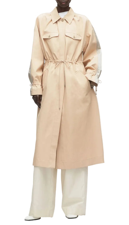 A person wears the 3.1 Phillip Lim Blouson Trench Coat in cotton-viscose twill, featuring front pockets and a cinched waist, styled over wide-leg white pants and white shoes, against a white background.