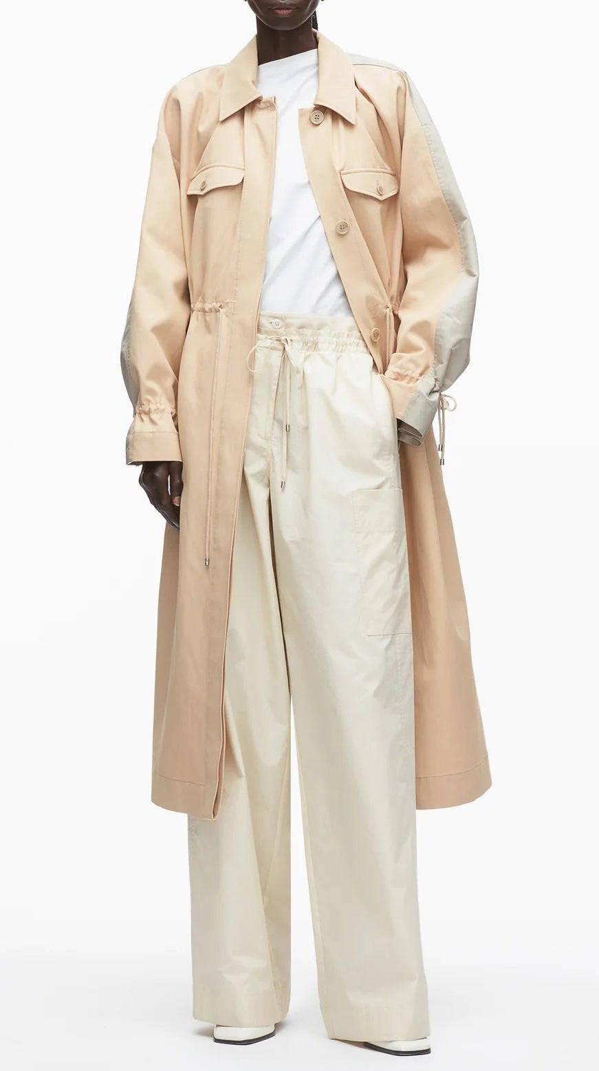 A person wears the 3.1 Phillip Lim Blouson Trench Coat over a white t-shirt and loose cream pants, standing against a plain white background.