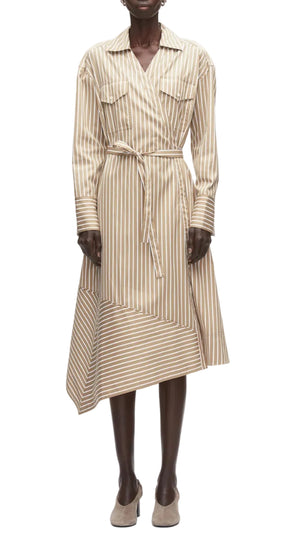 A person wears the 3.1 Phillip Lim Stripe Poplin Asymmetrical Wrap Shirt Dress—beige and white striped cotton poplin with a belted waist and handkerchief hem—paired with beige shoes.
