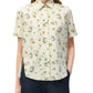 An effortlessly chic look featuring the Charlie Top by Adam Lippes—a short-sleeve, collared button-up shirt in cream, adorned with floral and animal prints—styled with dark pants.