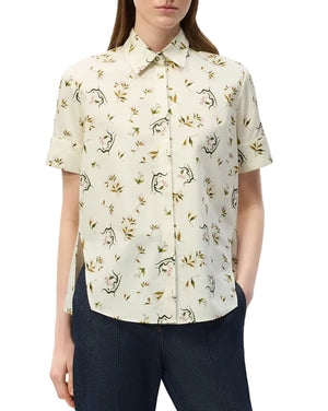 An effortlessly chic look featuring the Charlie Top by Adam Lippes—a short-sleeve, collared button-up shirt in cream, adorned with floral and animal prints—styled with dark pants.