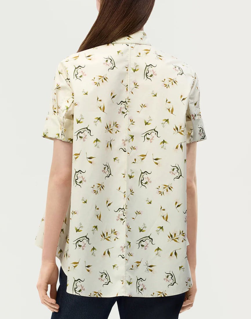 A person is shown from the back against a plain background, wearing the Adam Lippes Charlie Top— a light-colored collared blouse adorned with a subtle floral and line drawing pattern.