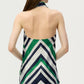 A woman is seen from behind wearing the Adam Lippes Cusette Printed Silk Twill Top, which features green, navy, and white diagonal stripes. Crafted from luxurious silk twill, the halter neck top has a backless design with an elegant bias drape and is styled with a coordinating skirt.