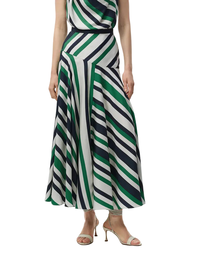A person is wearing the Adam Lippes Thea Printed Silk Twill Skirt, featuring diagonal green, navy, and white stripes reminiscent of Italian silk, styled with open-toe heeled sandals.