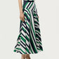 A person wearing a sleeveless top and the Adam Lippes Thea Printed Silk Twill Skirt, an Italian silk skirt with green, white, and navy diagonal stripes in a flared silhouette, paired with beige heeled sandals.