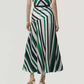 A person wearing the Adam Lippes Thea Printed Silk Twill Skirt, featuring diagonal green, black, and white stripes, stands facing away to highlight its flared silhouette and dynamic pattern—evoking the elegance of Italian silk.