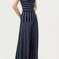 A woman stands against a plain background in the Gemma Compact Jacquard Dress by Adam Lippes, styled with black heeled sandals for an effortlessly chic look reminiscent of a navy jumpsuit.