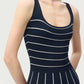 A woman wearing the Adam Lippes Gemma Compact Jacquard Dress, a sleeveless navy fit-and-flare style featuring horizontal white stripes on the bodice and vertical stripes on the skirt, photographed from the shoulders to mid-thigh.