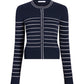 The Faye Cardigan by Adam Lippes is a navy jacquard knit cardigan with long sleeves and white horizontal stripes, featuring a button-down front and a round neckline.