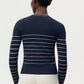 A person is seen from behind, wearing the Adam Lippes Faye Cardigan—featuring navy and white horizontal stripes—with off-white pants, standing against a plain light background.