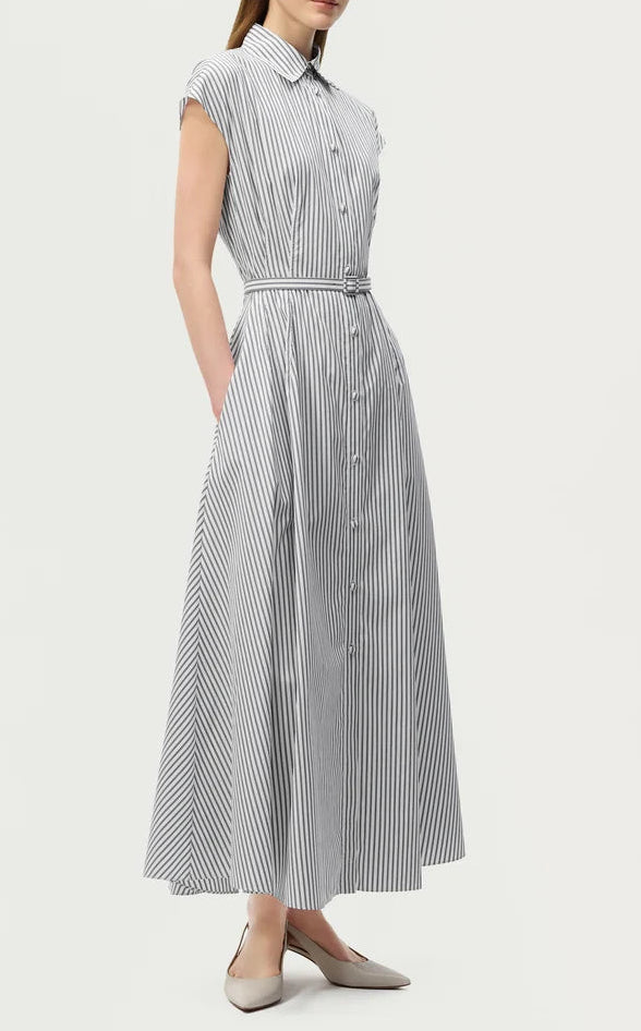 A woman wearing the Adam Lippes Palmer Stripe Shirting Dress—an ankle-length, sleeveless, button-down dress crafted from fine Italian cotton shirting and finished with a belted waist—paired with pointed-toe flats for an elegant, elongated silhouette.