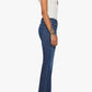 A woman standing in profile wears the Lil’ Weekender dark blue denim flare jeans by Mother with a white tank top and black heels against a plain white background.