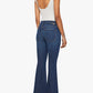 A woman stands facing away, wearing the Lil’ Weekender mid rise dark blue denim flare jeans by Mother, styled with a white sleeveless top and black heeled sandals against a plain white background.