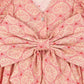 Close-up of the Girls' Ava Bow Dress by Konges Slojd, made from soft cotton with pink heart motifs, a V-neck with buttons, puffed sleeves, frill details, and a large back bow.