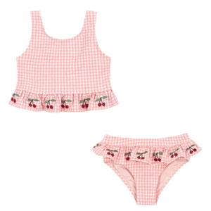 The Konges Slojd Girls' Soline Bikini features pink gingham seersucker fabric with a sleeveless top and matching bottoms, both adorned with cherry embroidery and frill accents.