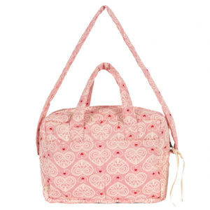 The Konges Slojd Lacy Pink Doll Bag is a quilted pink carryall with soft straps, grab handle, heart pattern, and front pocket—perfect for stylish doll outings.